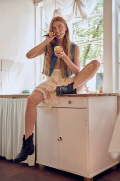 Woman Sitting on Counter Eating apple