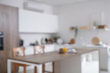Blurred view of light kitchen with counters, table and plants