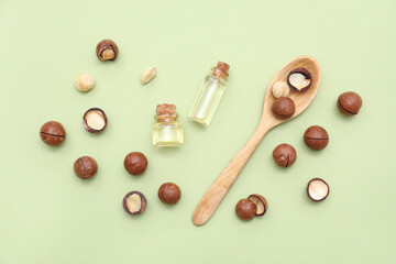 Bottles of macadamia oil and nuts on green background