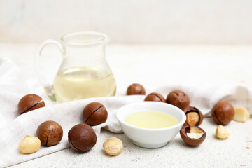 Napkin, jug and bowl of macadamia oil on grunge table, closeup