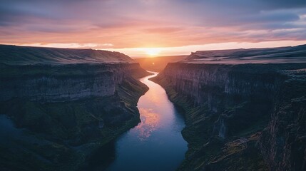 Fototapeta premium The sun descends beyond a canyon, where a river meanders between the distant mountain range