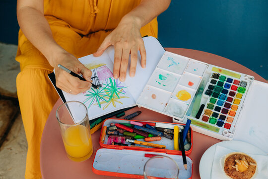 Anonymous female illustrator drawing in a paper notebook
