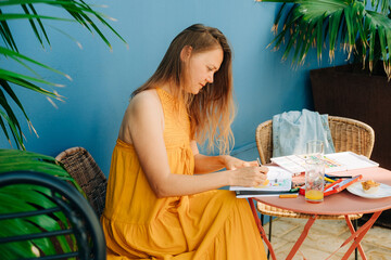Female illustrator working in a patio, making drawings in sketch