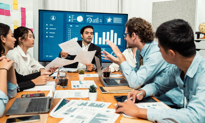 Diverse group of business analyst team analyzing financial data report. Finance data analysis chart and graph dashboard show on TV screen in meeting room for strategic marketing planning. Habiliment