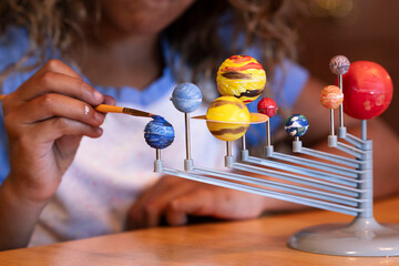 Young girl painting solar system model