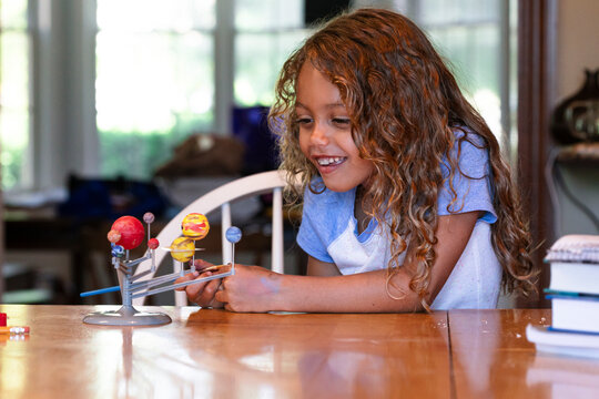 Young girl painting solar system model