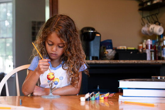 Young girl painting solar system model