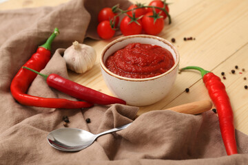 Bowl of chili sauce and different ingredients on wooden background