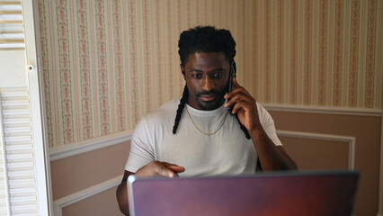 Man a sitting home working on phone and laptop