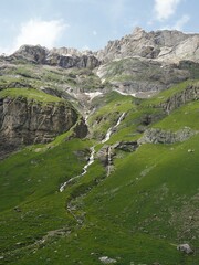 Waterfall flowing down on the rocks into a green valley