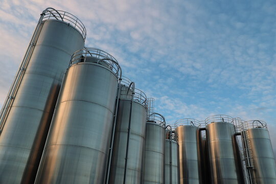 A row of large tanks are lined up against a blue sky