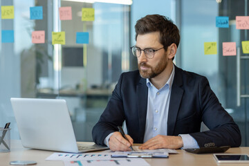 Focused businessman working on laptop in modern office setting