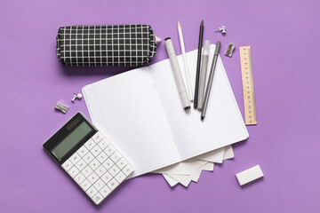 Blank notebook with pencil case and different stationery supplies on purple background