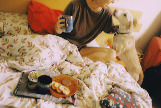 Woman and Dog Enjoying Breakfast in Bed With a Cup of Coffee