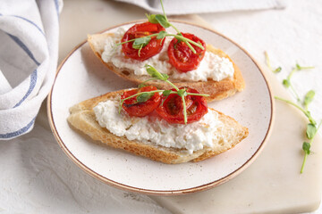 Plate of tasty tomato bruschetta with ricotta on white background