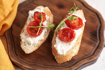 Wooden board of tasty tomato bruschetta with ricotta on table