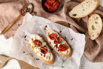 Wooden board of tasty tomato bruschetta with ricotta and peppercorn on table