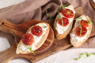 Wooden boards of tasty tomato bruschetta with ricotta and microgreens on white background