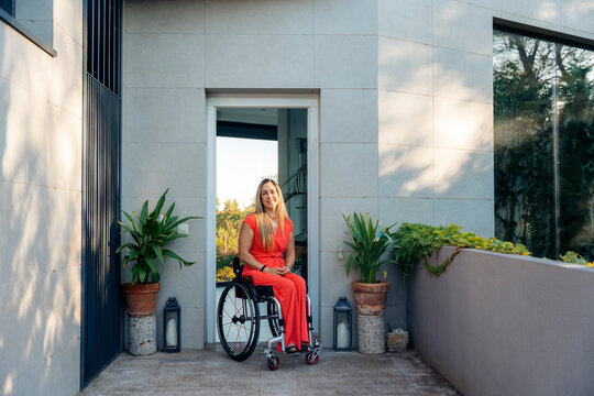 Woman in wheelchair smiling in a front door
