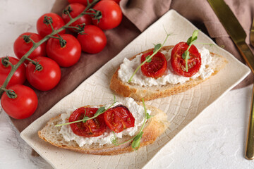 Plate of tasty tomato bruschetta with ricotta on white background