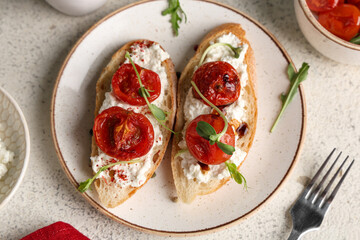 Plate of tasty tomato bruschetta with ricotta on white background
