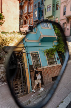 Man Reflected in Car Mirror on Colorful Street

