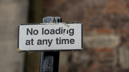 Weathered 'No Loading at Any Time' Sign with Moss Growth on Urban Post