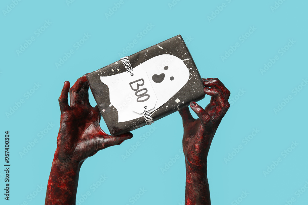 Wall mural hands of zombie with gift box and ghost made of paper on blue background. halloween celebration