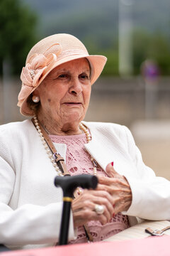 Elegant senior woman with her walking stick is sitting outside
