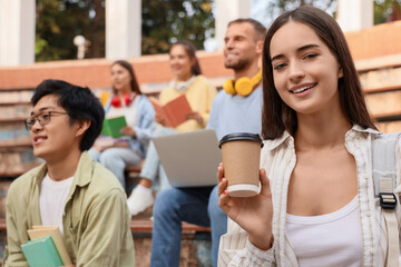 Female student with coffee cup having lecture outdoors, closeup