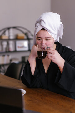 Close-up of plus size woman drinking coffee in front of laptop