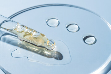 glass pipette dropper close up and Liquid yellow-orange retinol or vitamin c gel or serum on a...