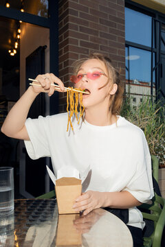 Woman Eating Noodles with Chopsticks Outdoors