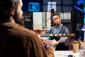 Fototapeta premium Cybersecurity professional helped by coworker during internet videocall to look for company security loopholes and injected viruses. Engineer and colleague in remote videoconference writing code on PC