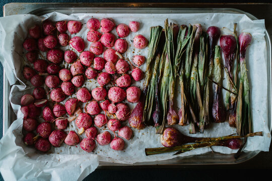 Baked radishes and spring onions on parchment paper