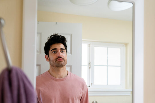 Man looking in bathroom mirror at home