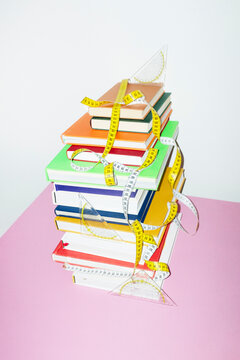 Stack of colorful books and measurement scale tapes on office desk