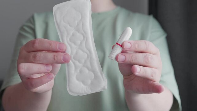 woman holding hygiene pad and tampon making decision of hygienic products choosing menstrual cup. choose alternative eco friendly variant of protection during menstruation.