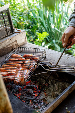 Anonymous person frying sausages on a charcoal grill. Street food.
