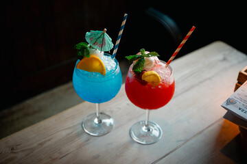 Colorful Red and Blue Cocktails in a Cozy Pub Setting: Refreshing Drinks with Garnishes, Perfect for a Night Out with Friends