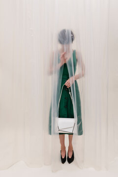 Mysterious Woman Behind Sheer Curtain Holding White Handbag