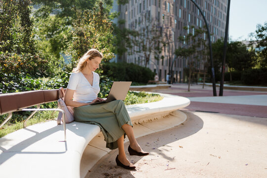 Businesswoman using a laptop while sitting on a bench at the park