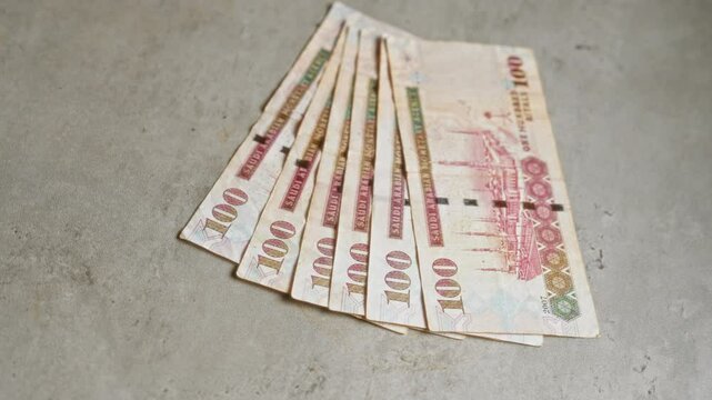 Saudi arabian riyal banknotes fanned out on a concrete surface, showcasing the intricate design of currency from saudi arabia.
