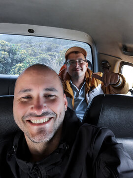 Two cheerful men taking a selfie inside a car
