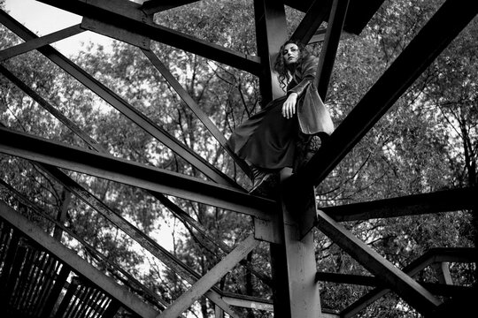 A girl perching on metal tower in the woods.