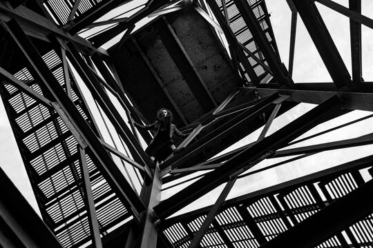 A girl in the metal pattern of a staircase.