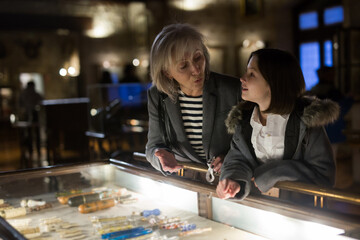 Fototapeta premium Friendly aged female tutor helping preteen girl exploring antique showpieces in local history museum..