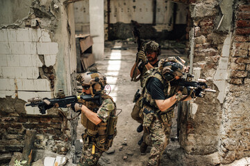 Top view of air soft team with rifles shooting at ruined building.