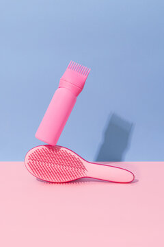 Pink hairbrush with matching hair clipper on pastel backdrop