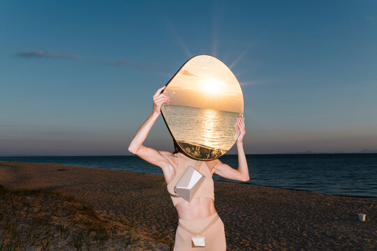 Surreal Beach Scene with Woman Holding Mirror at Sunset